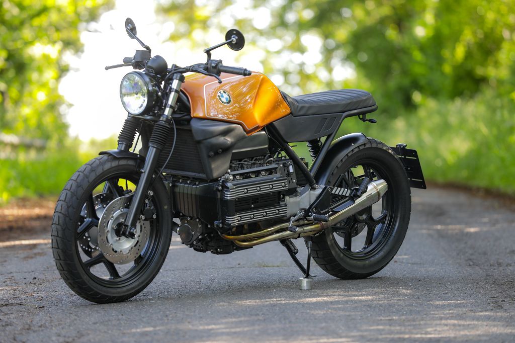 BMW K100 SE Roadster bike in vibrant orange color, showcasing custom design and powerful engine on scenic road.