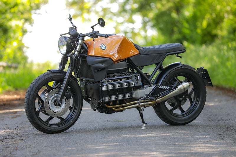 BMW K100 SE Roadster bike in an outdoor setting, showcasing a unique orange and black design with a modern aesthetic.