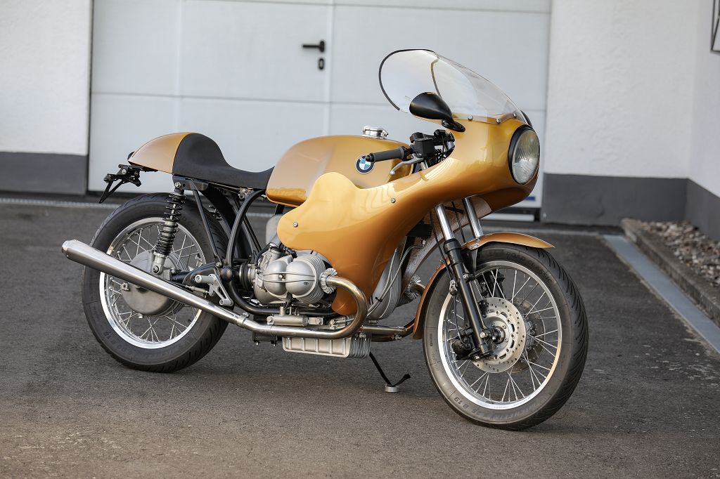 BMW Bobber SE Concept Bike in classic racer gold finish parked in front of a garage.