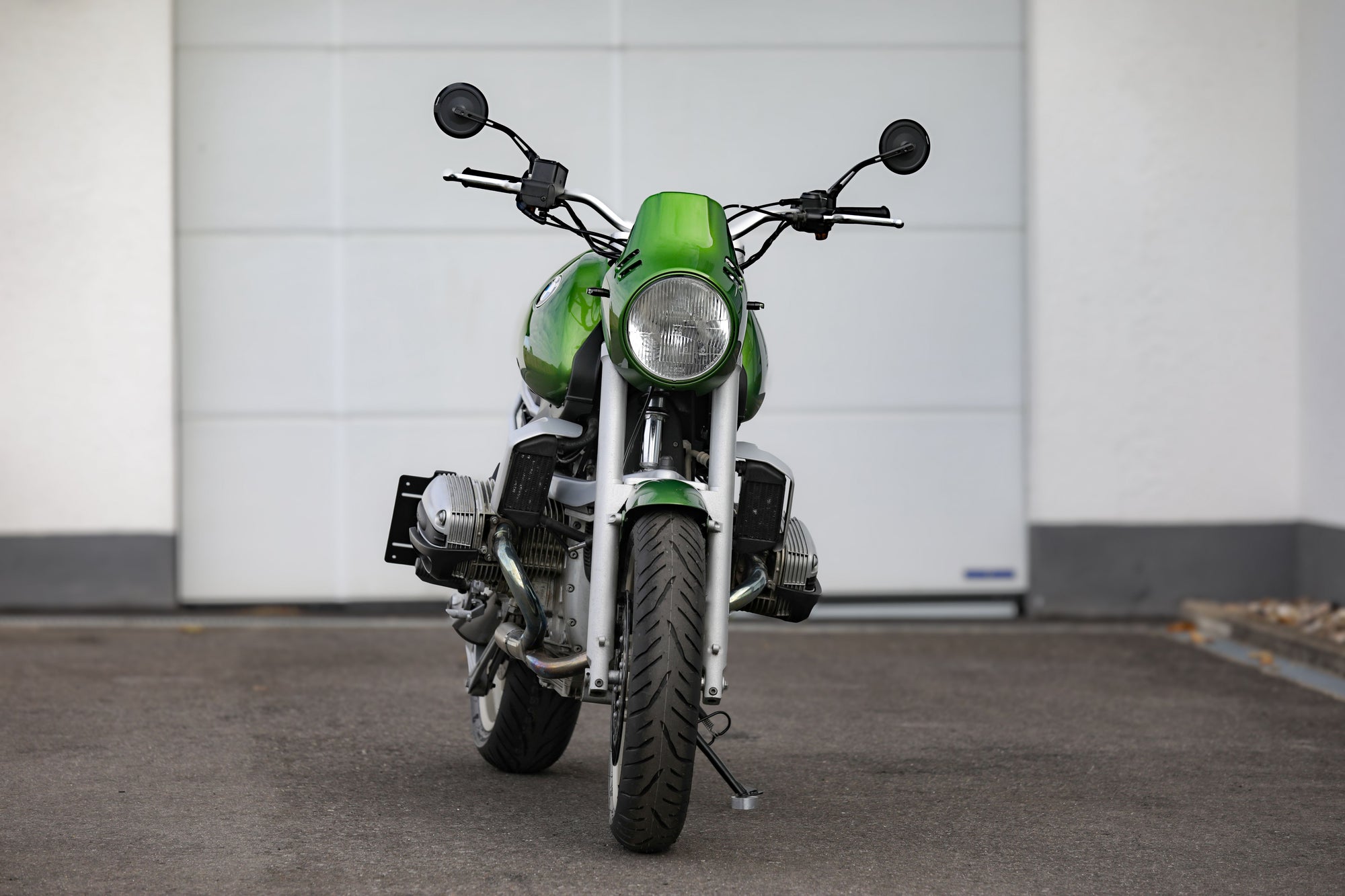BMW R1100R Telelever motorcycle custom in green color, captured from the front view in a parking area.